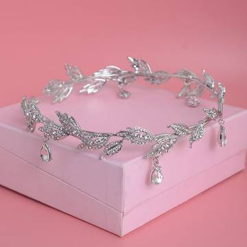 a tiara with leaves and pearls on a pink background