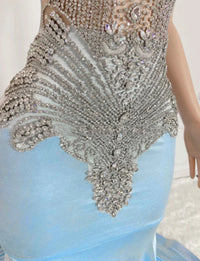 a woman wearing a blue dress with silver beads on it