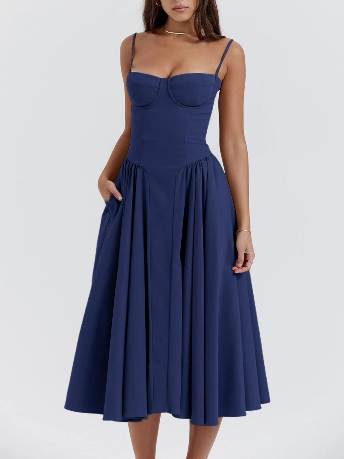 Model wearing a ruched sweetheart neck cami dress in navy blue with a flowy skirt and pockets.