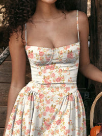 Woman wearing floral ruched sweetheart neck cami dress with spaghetti straps.