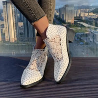 White printed point toe block heel boots with lace design, showcasing a stylish look against a city backdrop.
