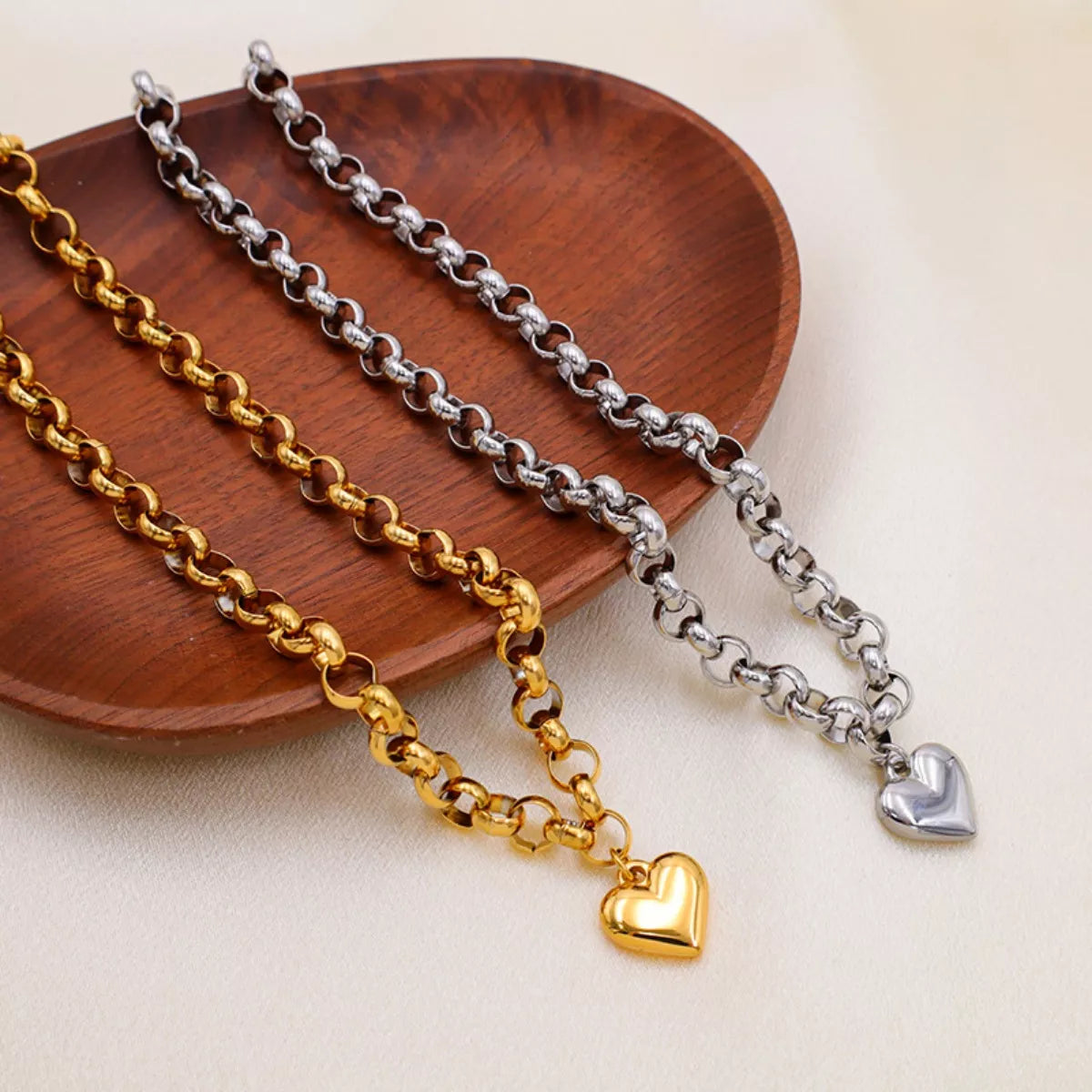 Heart Pendant Toggle Clasp Chain Necklace featuring gold and silver links elegantly displayed on a wooden plate.