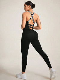 Back view of a woman in a black crisscross back sleeveless active jumpsuit with sporty branding.
