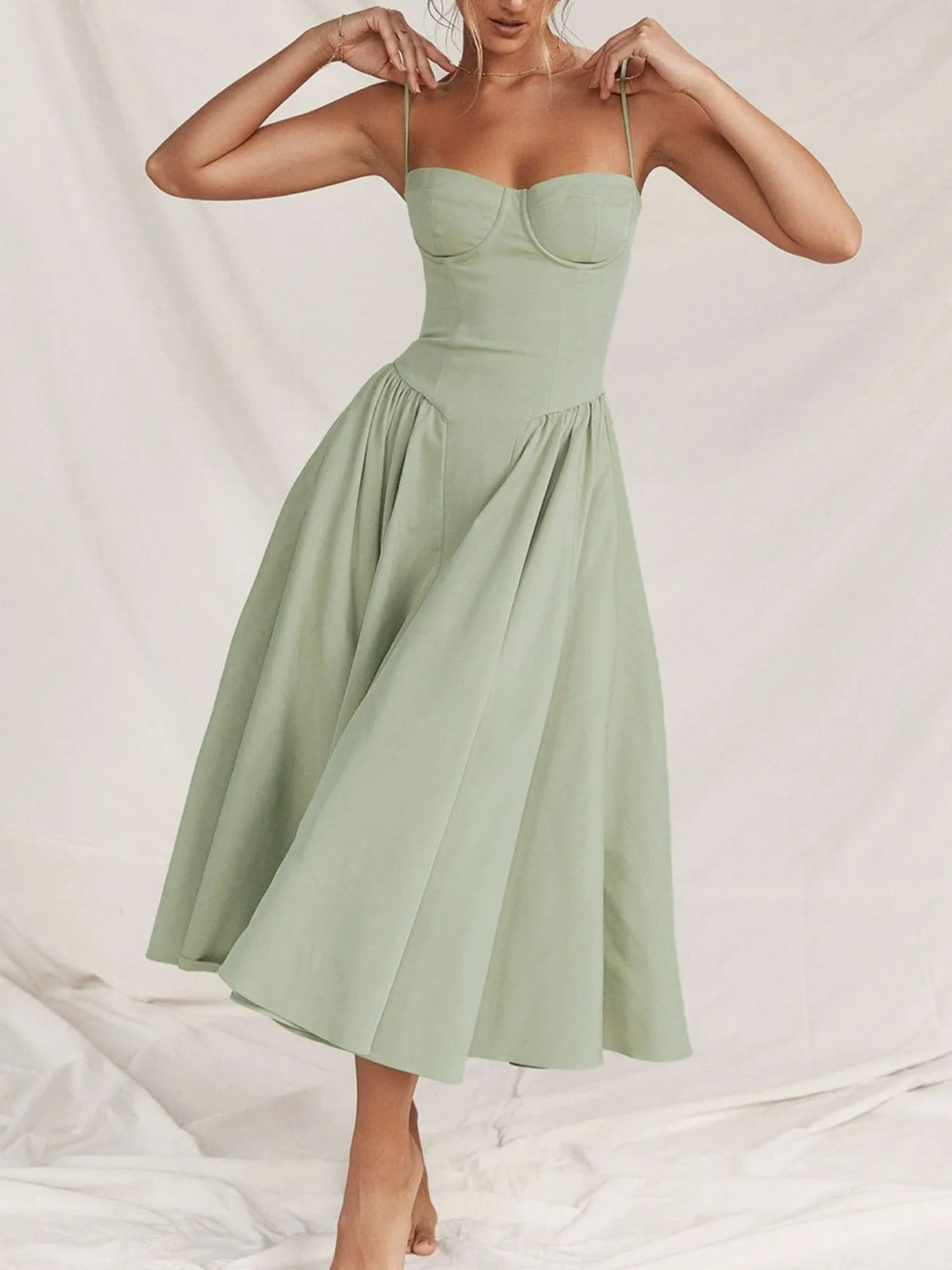 Ruched sweetheart neck cami dress in light green, featuring adjustable straps and a flowing skirt.