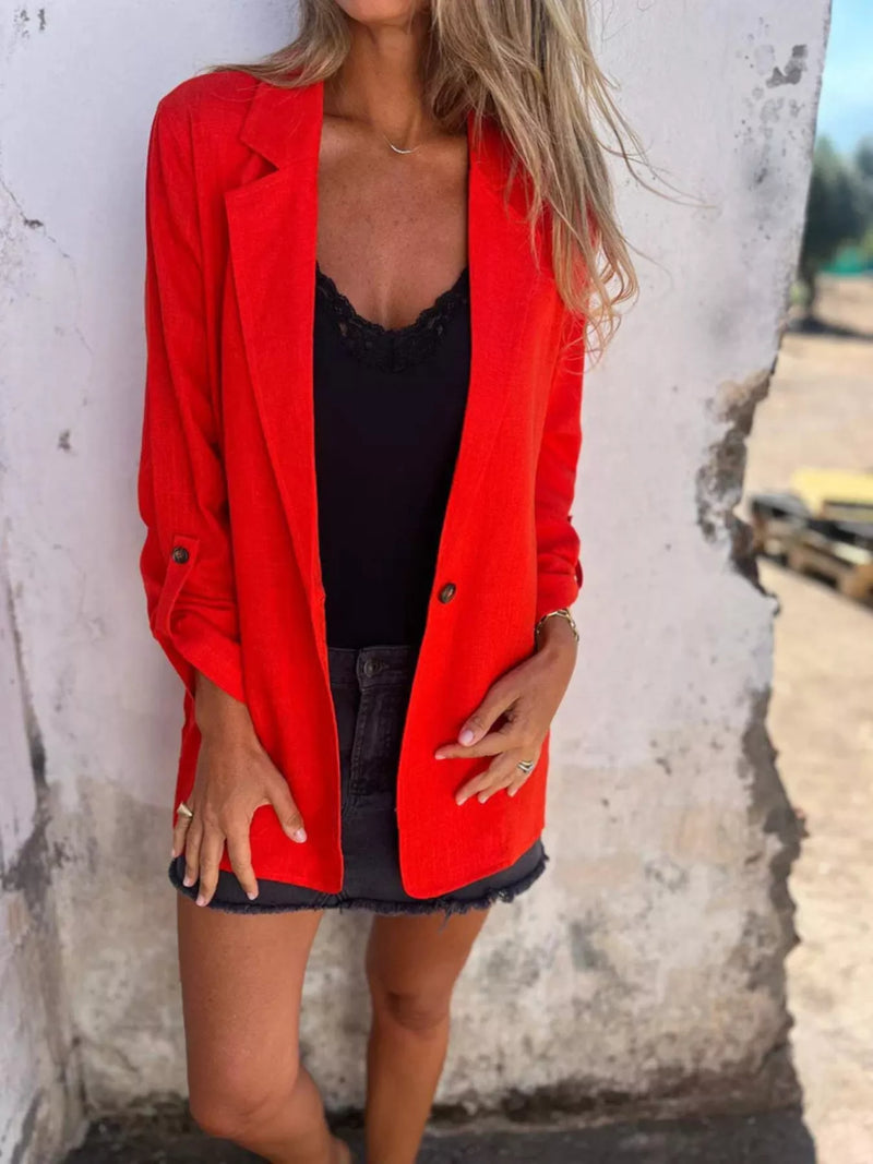 Woman wearing a bright red lapel collar blazer over a black top and denim skirt, showcasing a stylish summer outfit.