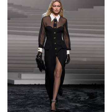 a woman in a black dress and gloves on a runway