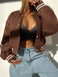 Stylish brown snap down long sleeve jacket paired with a black top and light blue jeans, perfect for upscale events.