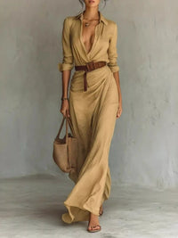 Full Size Ruched Long Sleeve Maxi Dress Plus Size in beige with belt and tote bag, model walking on neutral background.