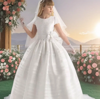 Flowergirl standing in her wedding gown holding a white love heart box 