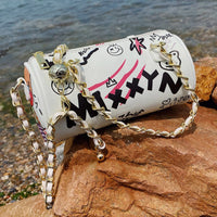 Graffiti cylindrical leather zipper crossbody bag styled for luxurious weddings by the water.