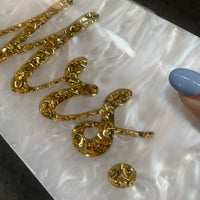 Close-up of luxurious Mrs letter design with gold sequins on white marble acrylic evening bag for weddings.