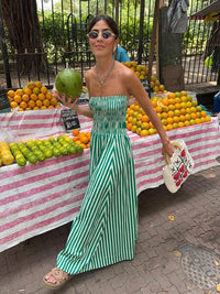 a woman in a green and white striped dress holding a green apple