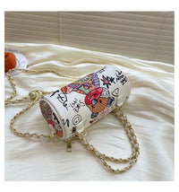 Graffiti cylindrical leather zipper crossbody bag on a silk surface, ideal for luxurious weddings.