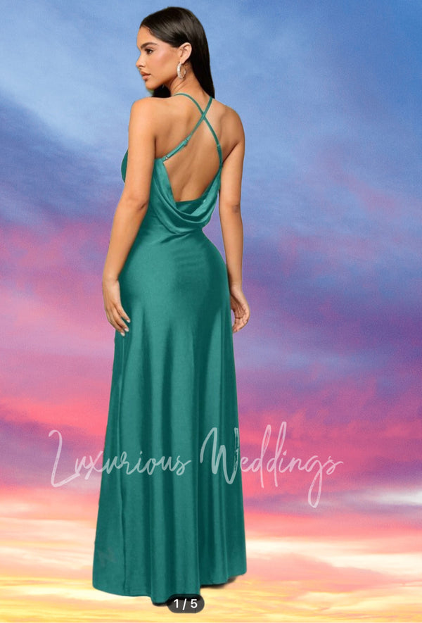 a woman in a long green dress standing in front of a sunset
