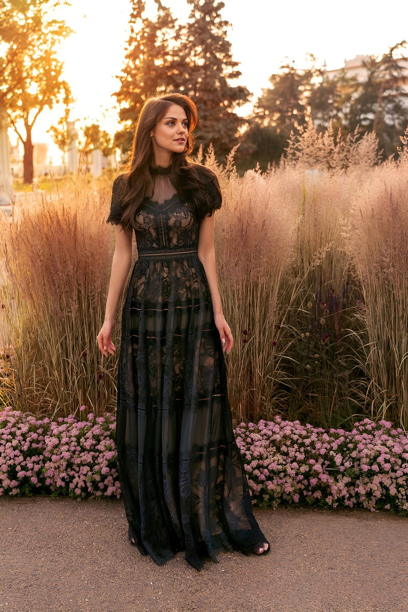Elegant black lace evening dress with short sleeves, perfect for formal occasions, surrounded by floral greenery.