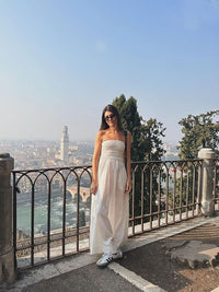 a woman in a white dress standing on a balcony