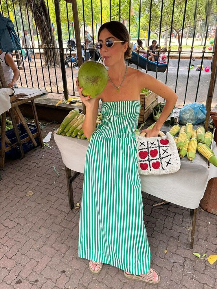 a woman in a green and white striped dress holding a coconut
