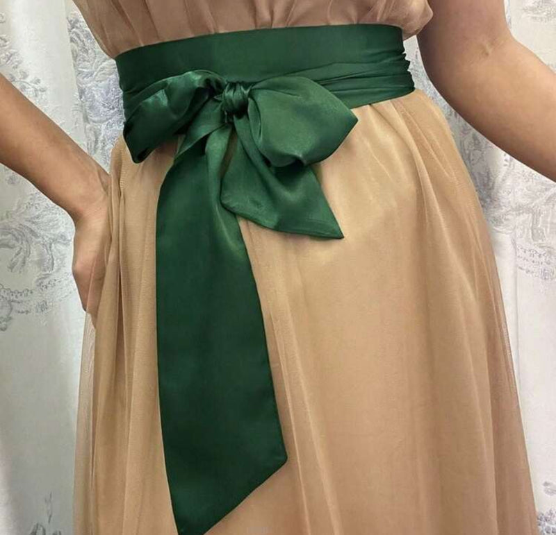 Green bridesmaid waist sash tied on a flowing beige dress, adding elegance and a flattering accent to the outfit.