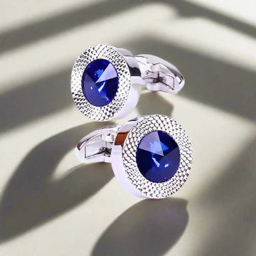 a pair of cufflinks with a blue stone