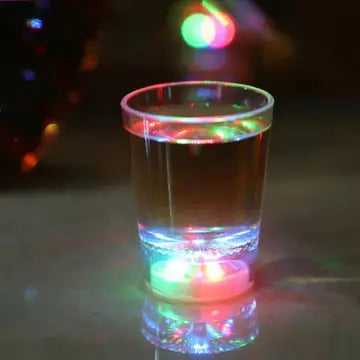 a glass of water with some lights in the background