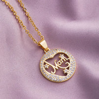 a gold necklace with a heart and the word mom on it