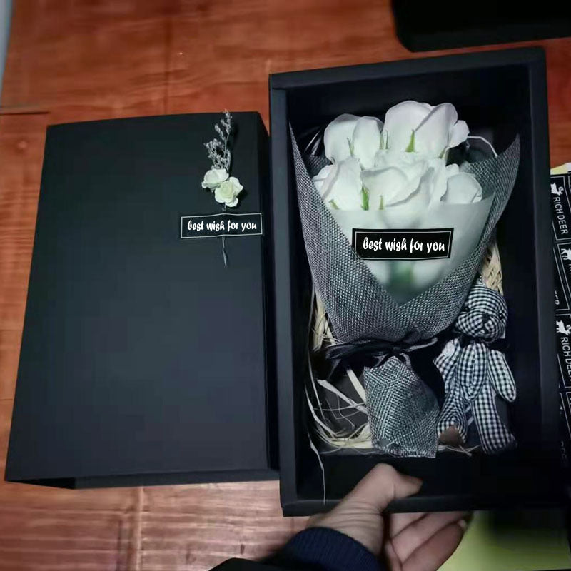 a person holding a bouquet of white roses in a black box