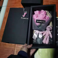 a person holding a pink teddy bear in a black box