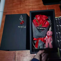 a person holding a bouquet of red roses in a black box