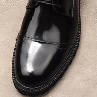 a close up of a black shoe on a white surface