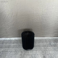 a black vase sitting on top of a floor next to a wall