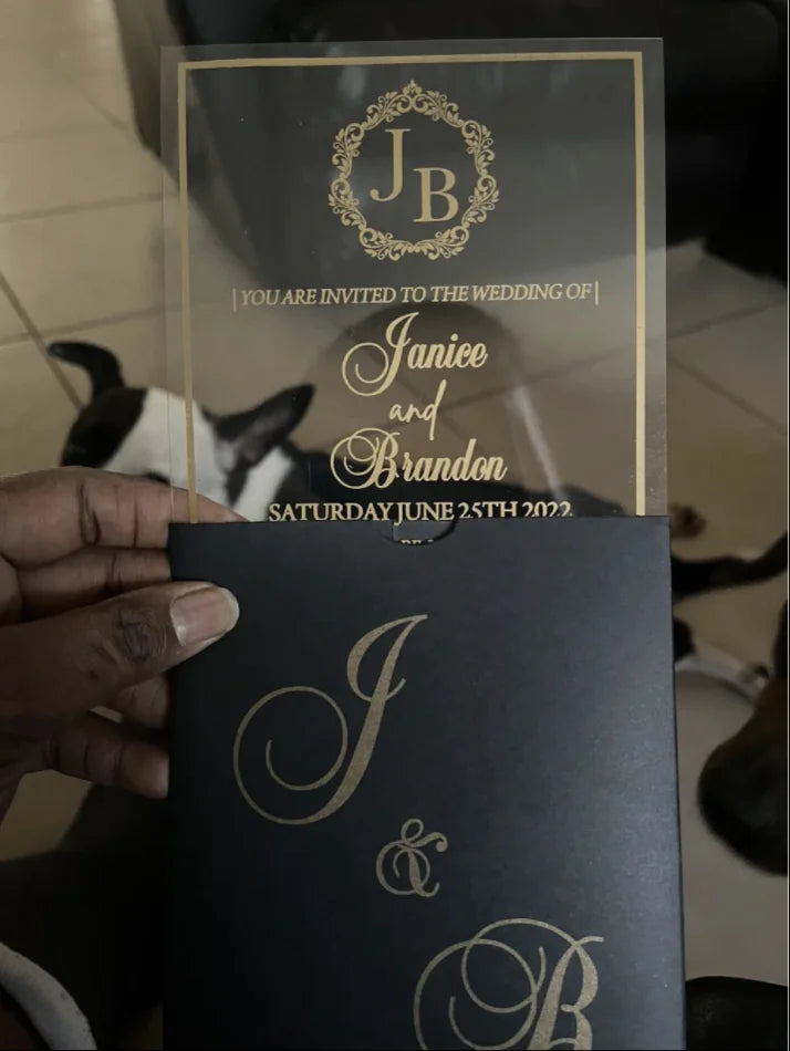 a person holding up a black and gold wedding card