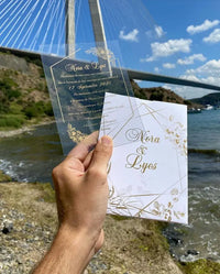 a person holding up a card in front of a bridge