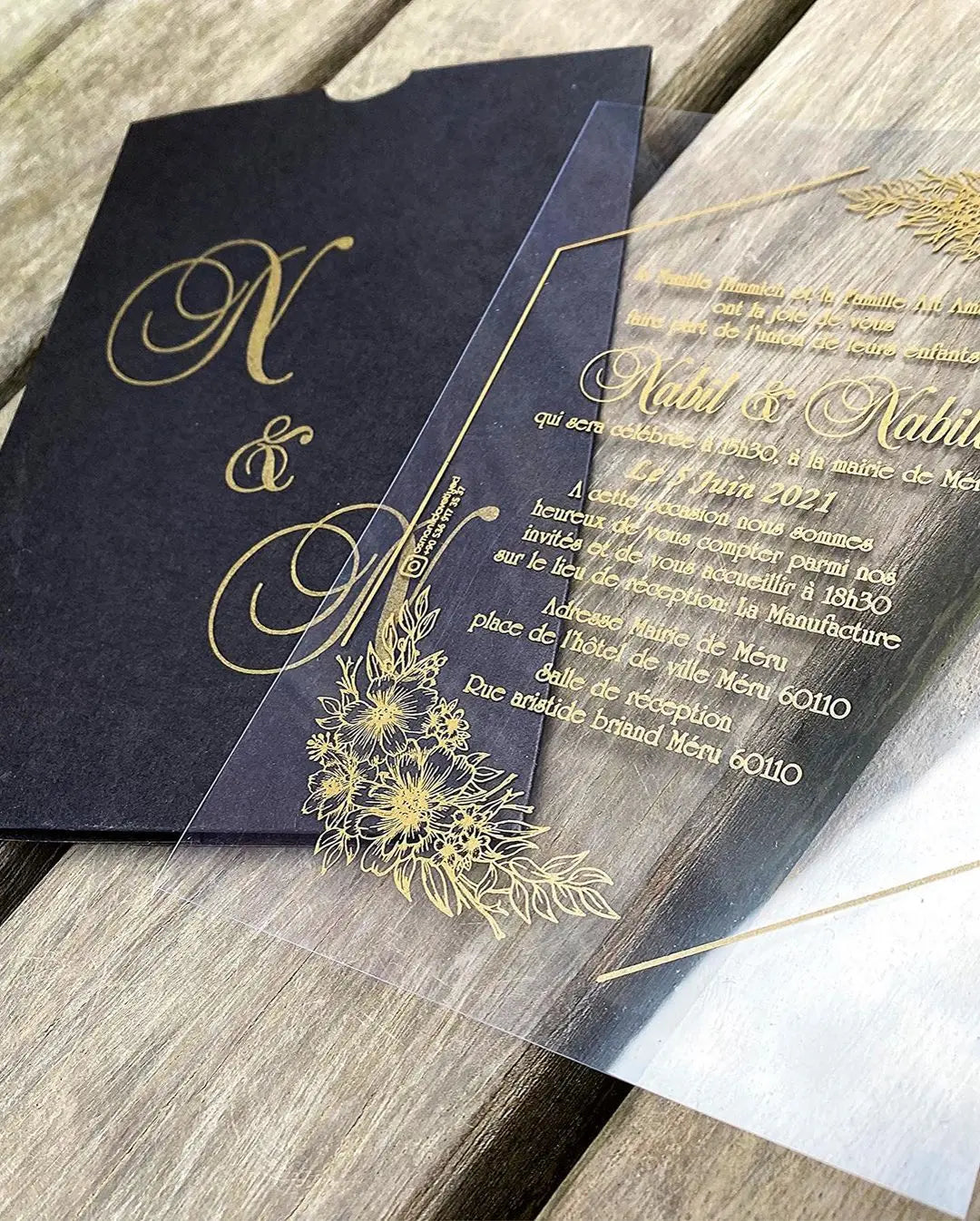 a black and gold wedding card on a wooden table