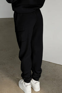 Black pocketed elastic waist active joggers, viewed from the back, paired with white sneakers.