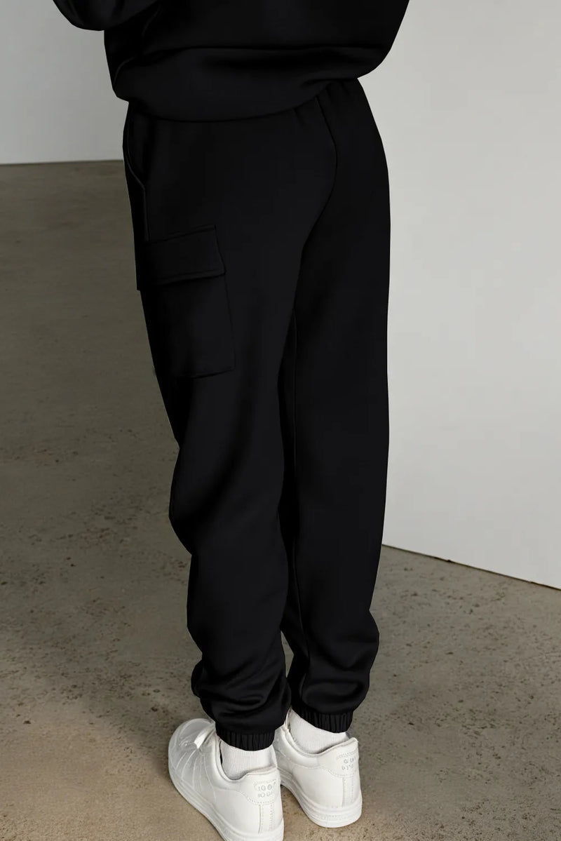 Black pocketed elastic waist active joggers, viewed from the back, paired with white sneakers.