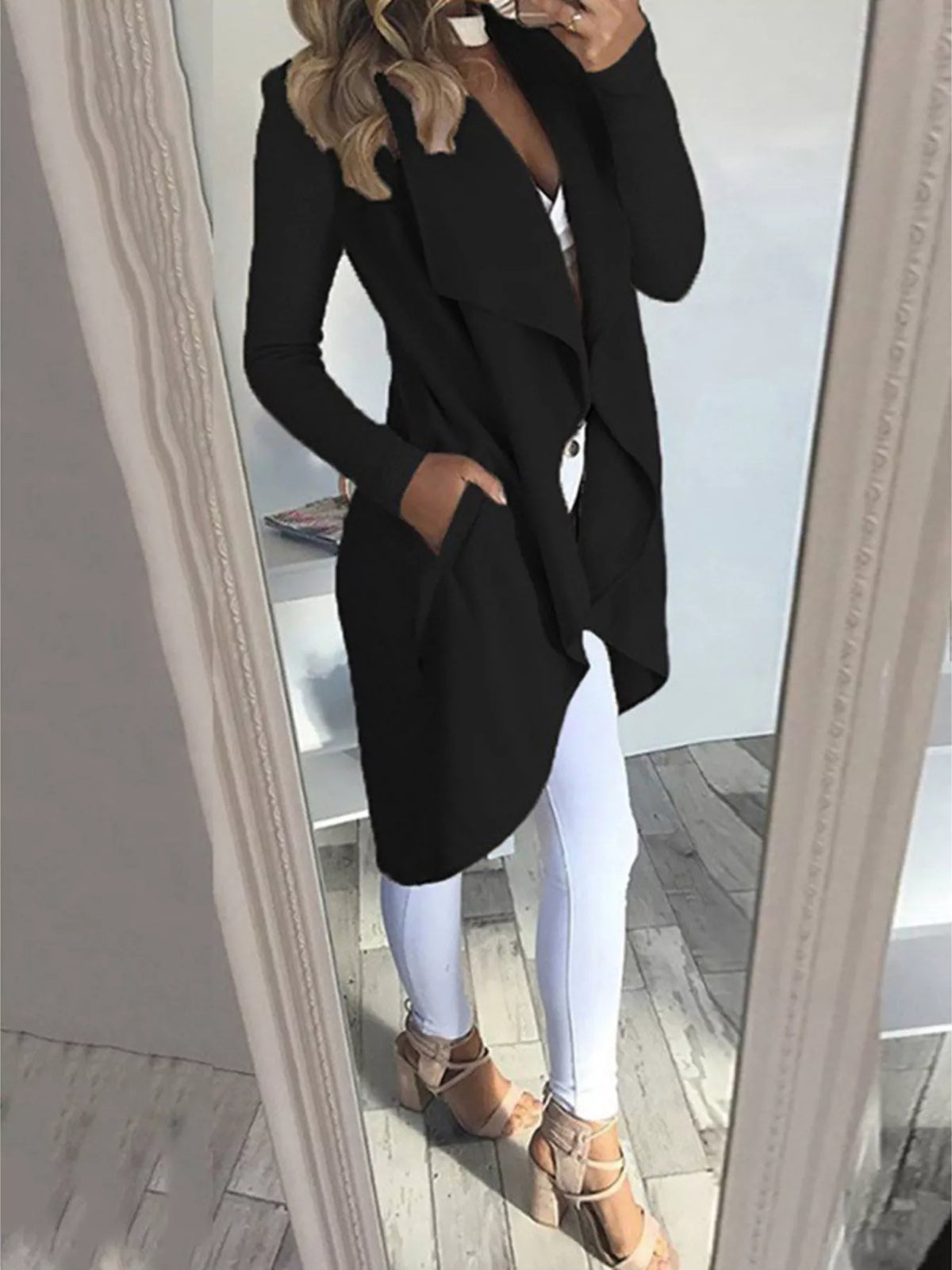 Plus size black lapel collar long sleeve coat, belted, pocketed, styled with white leggings and heels.