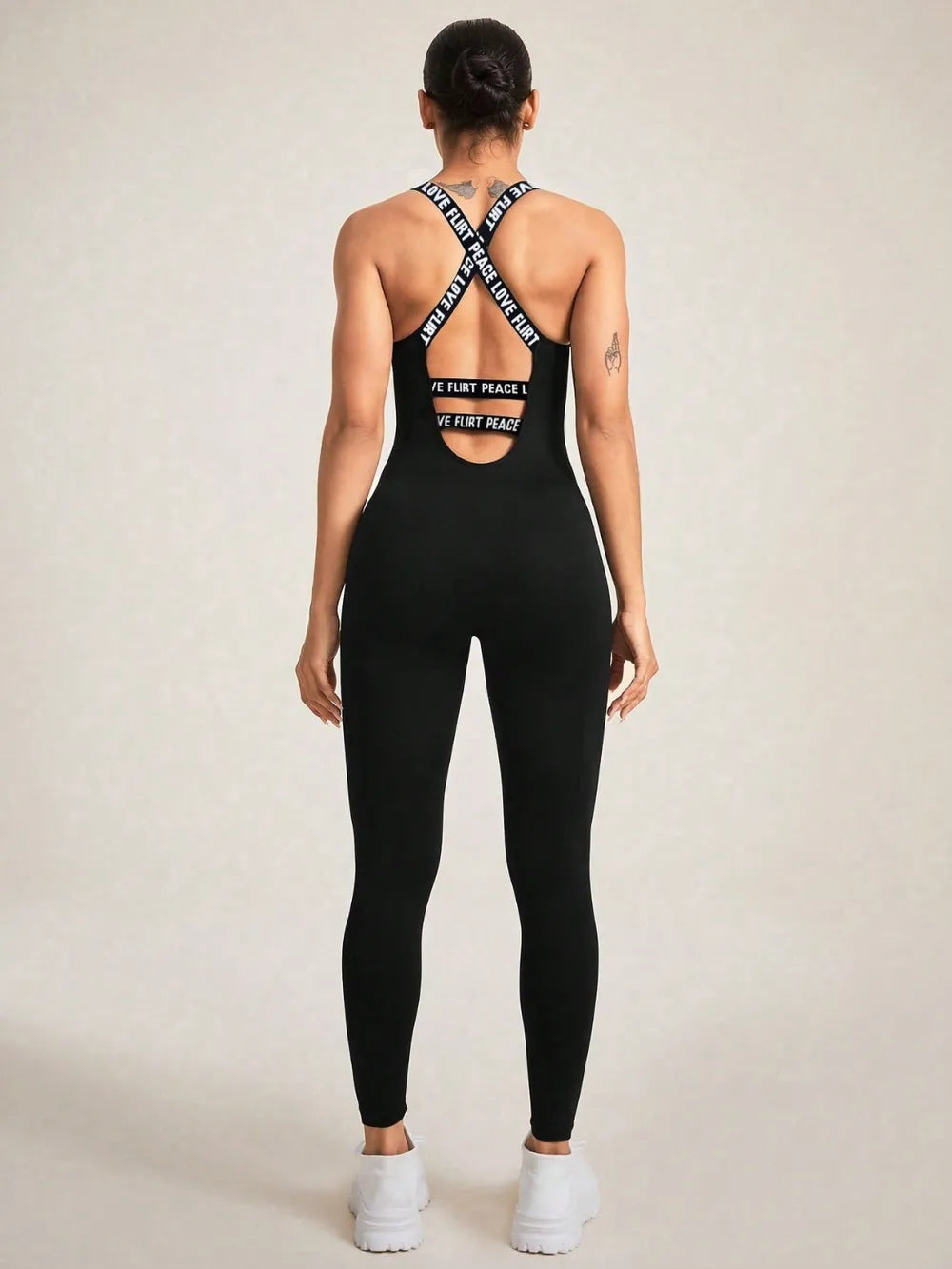 Back view of a woman in a crisscross back sleeveless active jumpsuit, showcasing its stretch design and comfortable fit.