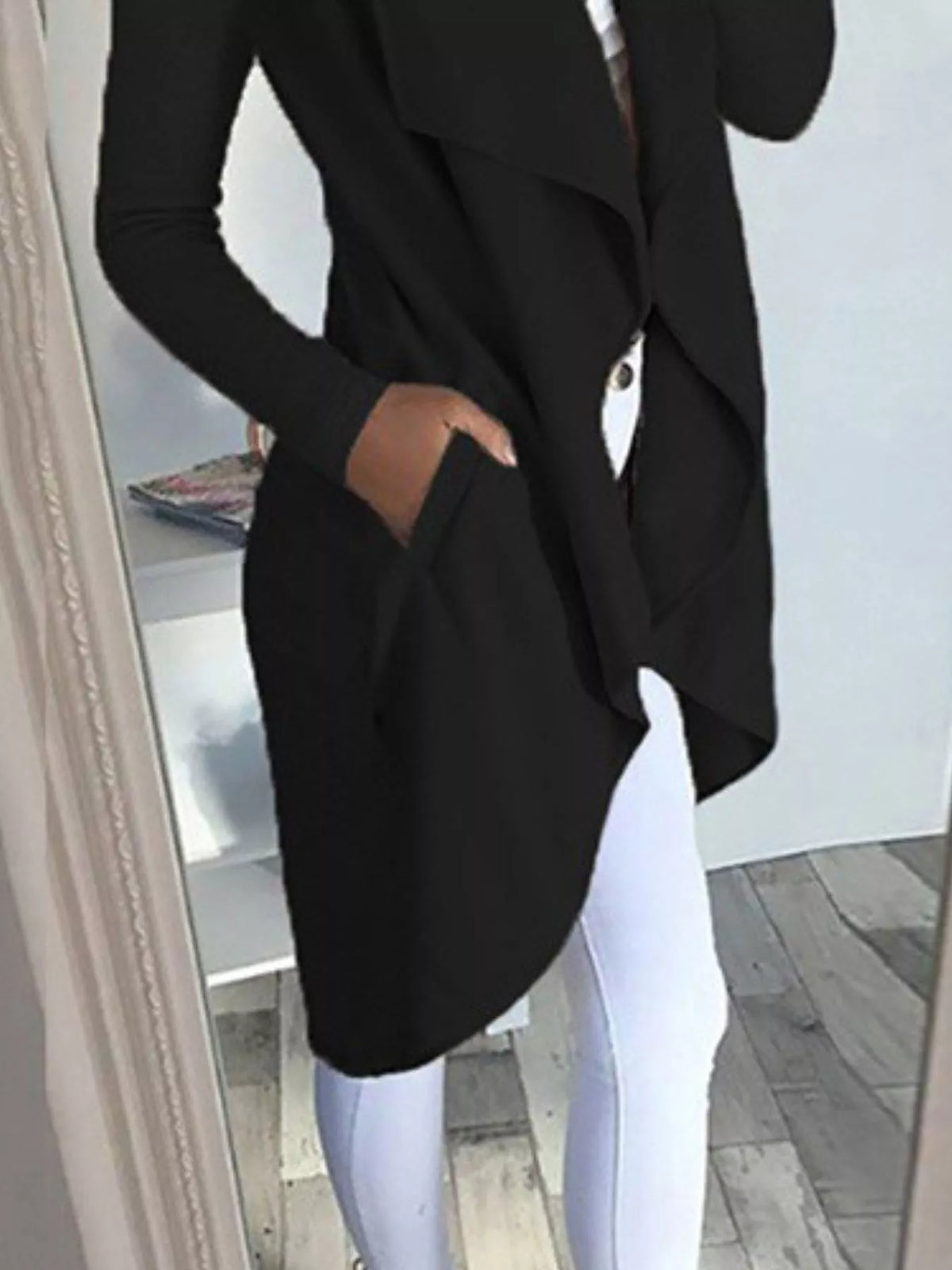 Full size lapel collar long sleeve coat in black with pockets, worn over white pants, showcasing stylish outfit.
