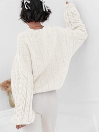 Back view of a model wearing a white cable knit long sleeve sweater, showcasing its textured design and relaxed fit.