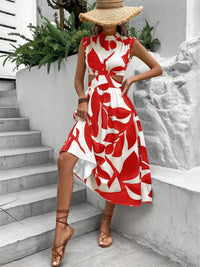 Model wearing a cutout printed sleeveless dress with bold red and white floral patterns, showcasing a stylish summer look.