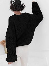 Woman wearing a black cable knit long sleeve sweater, showcasing the back design and relaxed fit.