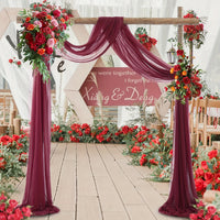 a wedding arch decorated with red flowers and greenery