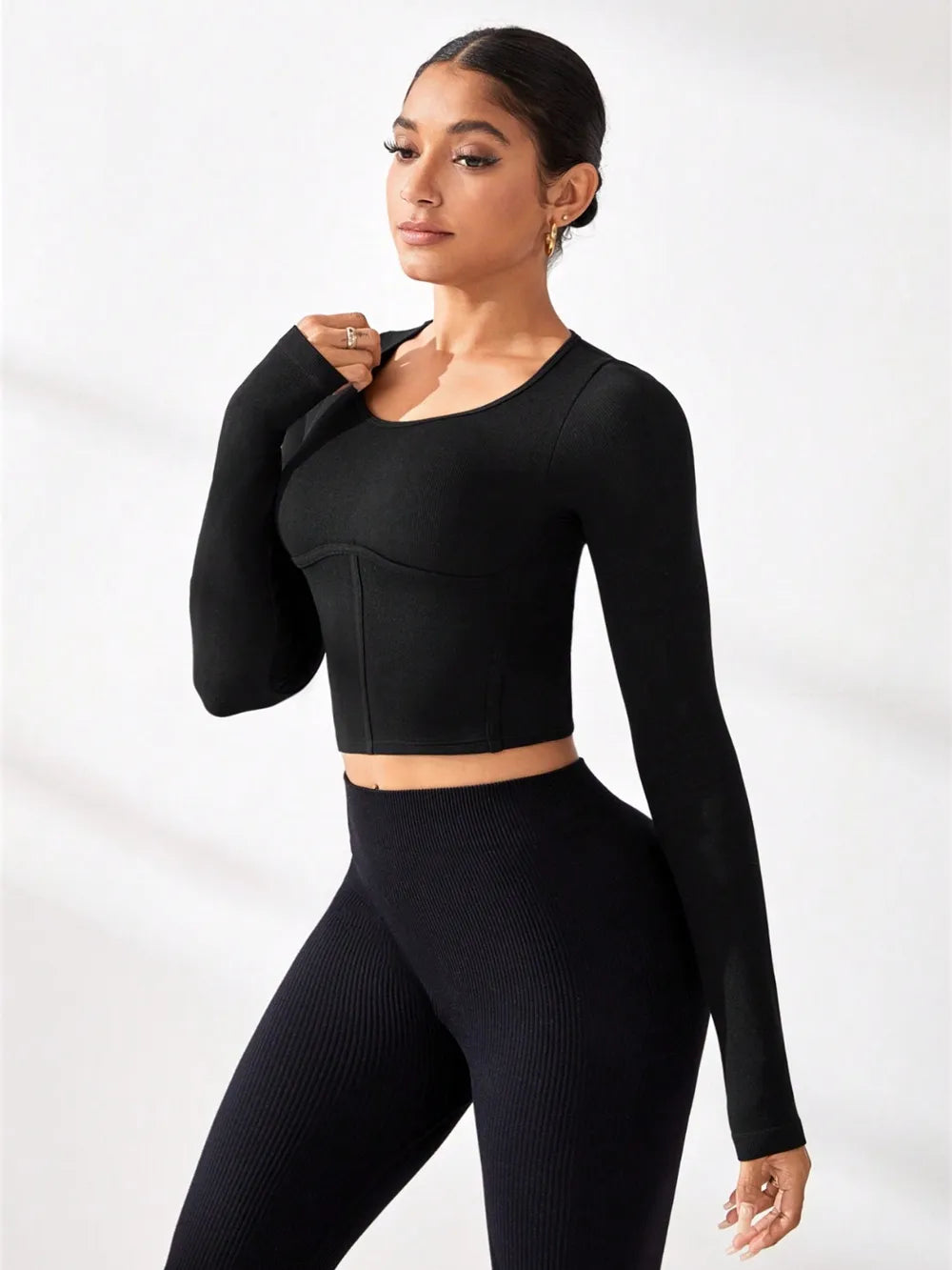 Model wearing a round neck long sleeve active T-shirt paired with ribbed leggings in black.
