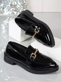 Point toe block heel loafers in glossy black patent leather with gold hardware accents.