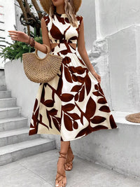 Stylish model wearing a cutout printed sleeveless dress with brown leaf patterns, holding a straw bag.