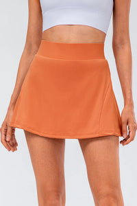 High waist pleated active skirt in orange, made of stretchy nylon-spandex blend, perfect for activewear.