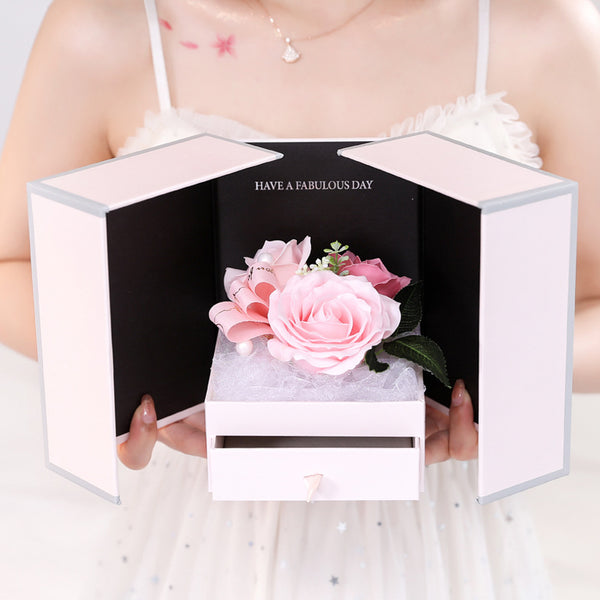 a woman holding a white box with a pink flower in it