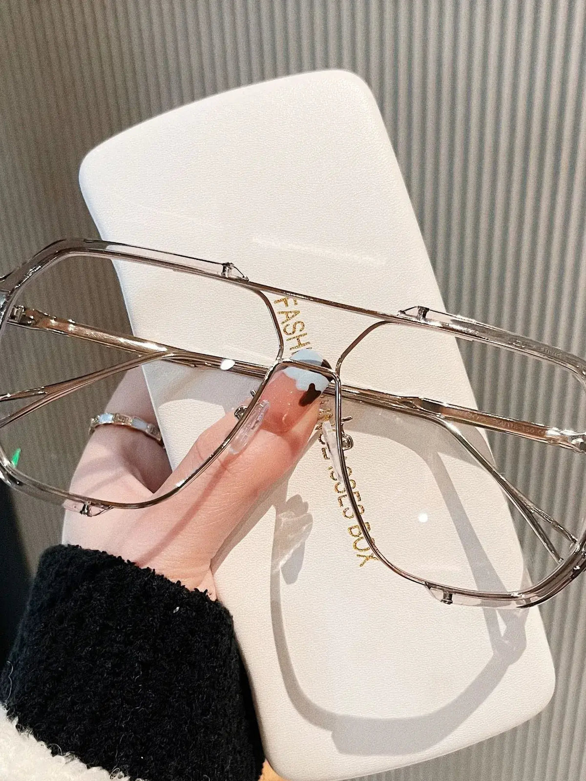 Hand holding oversized UV protection sunglasses with stylish frame and case, perfect for luxurious weddings and bridal boutiques.