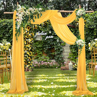 a yellow wedding arch decorated with flowers and greenery