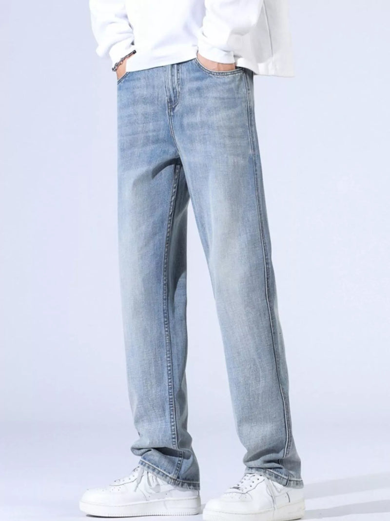 Men's relaxed fit wide leg jeans in light wash, styled with a white sweater and sneakers.